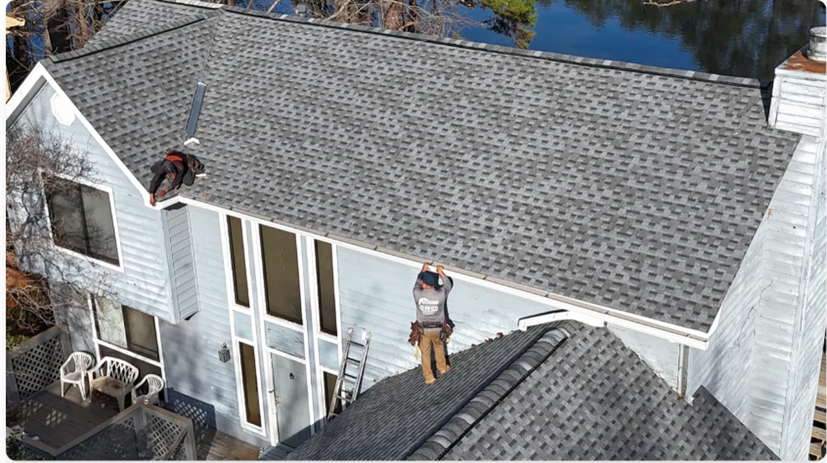 Crew installing seamless gutters along the roofline of a two-story home