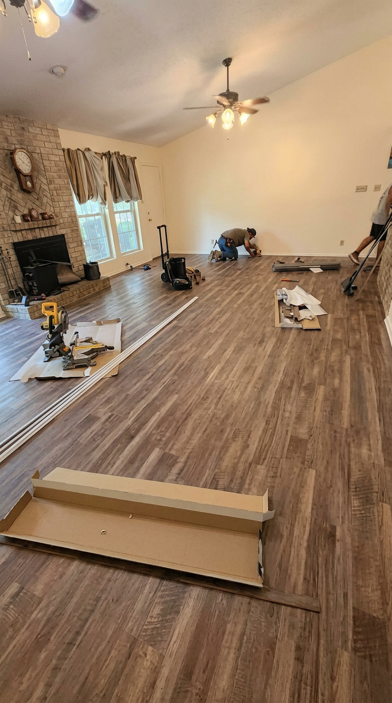 Living room flooring installation in progress with new wood-look planks being laid across the floor
